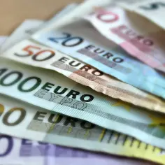 Banknoty euro o nominałach 100, 200, 50, 20 i 10 euro ułożone na stole.