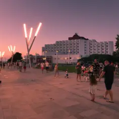 Spacerem po alei gwiazd w Międzyzdrojach o zachodzie słońca. Ludzie spacerują, dzieci się bawią, a nowoczesne latarnie oświetlają promenadę.