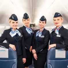 Uśmiechnięte stewardessy Enter Air w granatowych mundurach i chustach z logo linii. Gotowe do lotu czarterowego.