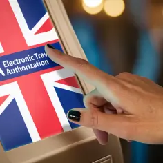 Dłoń dotyka ekranu z flagą Wielkiej Brytanii i napisem ETA. Czy do Londynu trzeba paszport? Sprawdź ETA!