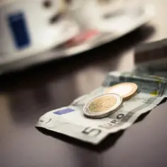 Na stole leży banknot 5 euro i dwie monety. To waluta w Grecji, używana do zapłaty za kawę.