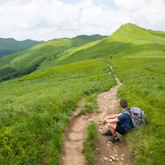 Chwila wytchnienia na szlaku. Gdzie w Bieszczady? Tu, na zielonych połoninach, gdzie droga wije się wśród traw.