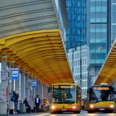 Warszawa dzisiaj: żółta wiata na przystanku, autobusy 525 i 131, nowoczesne wieżowce w tle.