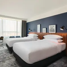 Pokój hotelowy w Sheraton Wrocław z dwoma łóżkami, biurkiem i oknem.