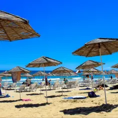 Słoneczna plaża w Bułgarii, pełna leżaków i parasoli. Ludzie odpoczywają, kąpiel w morzu jest bezpieczna.