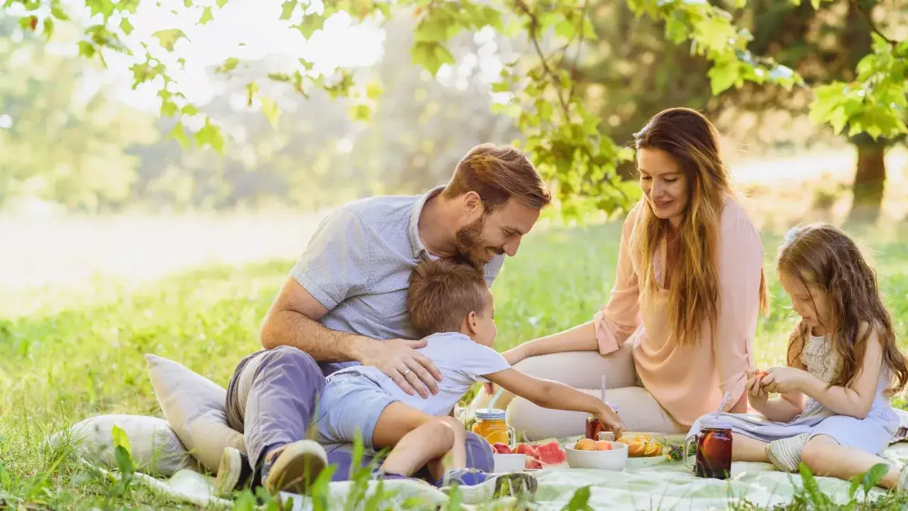Rodzina na pikniku. Tani weekend z dziećmi w słoneczny dzień. Radosne chwile na łonie natury.