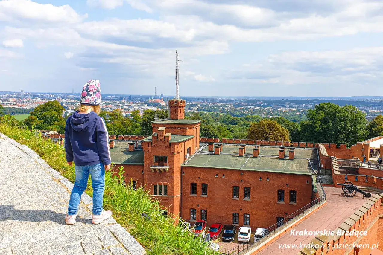 Dziecko podziwia panoramę Krakowa z fortu. To jedno z fajnych miejsc w Krakowie, idealne na rodzinne wycieczki.