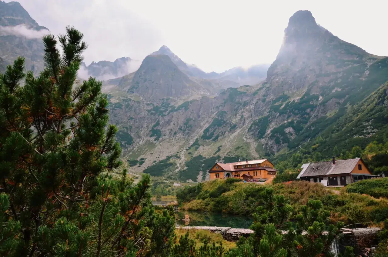 Malownicze tatry słowackie z górami, schroniskami i jeziorem w jesiennej scenerii.
