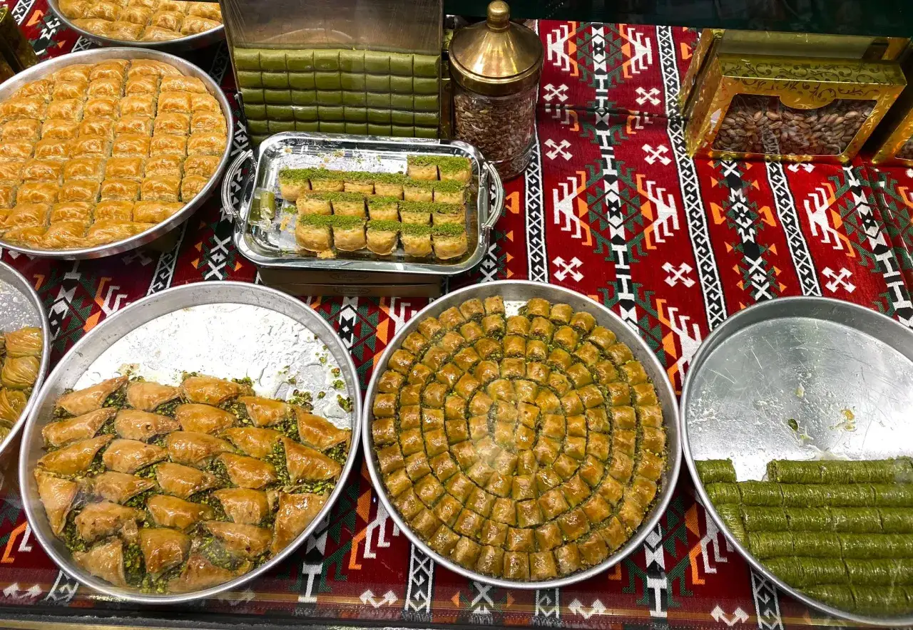 Mnóstwo pysznego, tureckiego jedzenia: baklawa w różnych kształtach, rolki z pistacjami i orzechy.