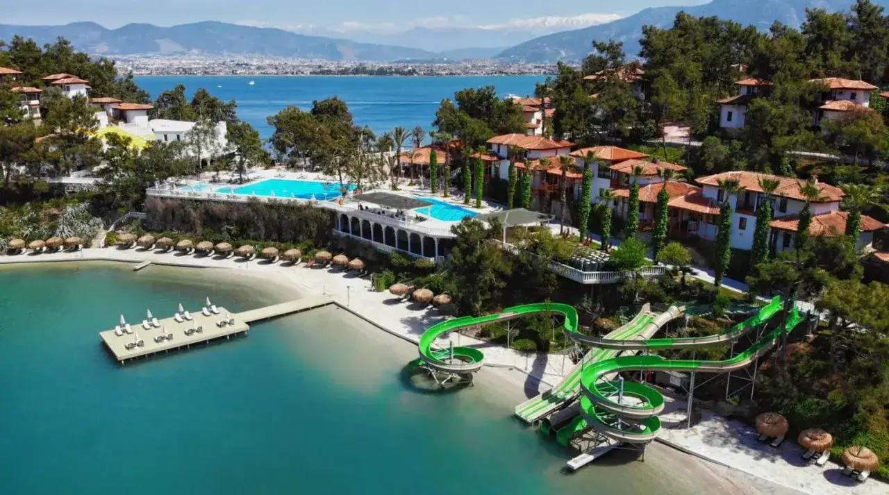 Letoonia Club & Hotel: baseny, zjeżdżalnie wodne i plaża z leżakami nad turkusowym morzem.