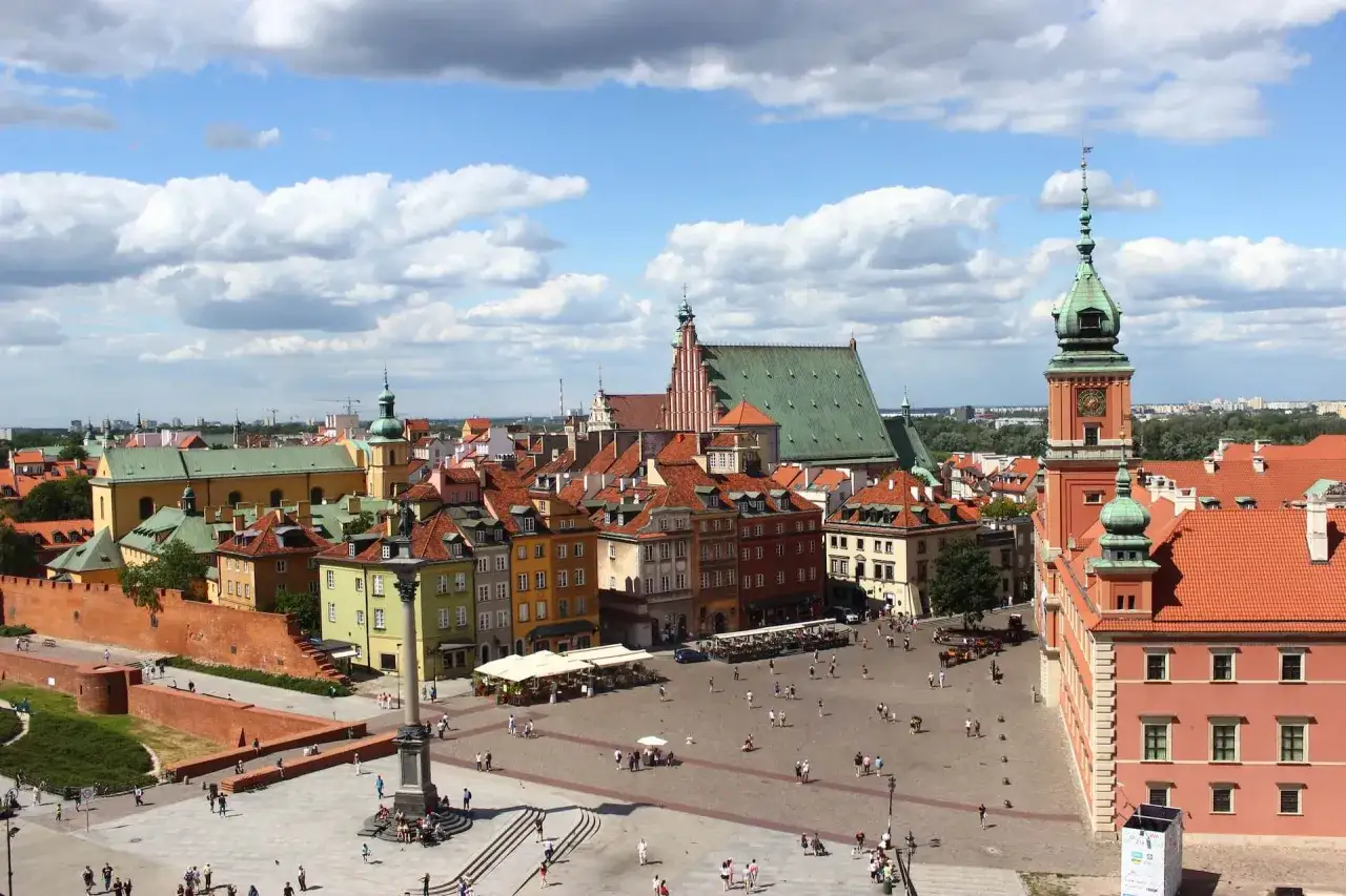Widok na Zamek Królewski i Kolumnę Zygmunta III Wazy na placu Zamkowym. Tętniąca życiem starówka warszawa z kolorowymi kamienicami i zielonymi dachami.